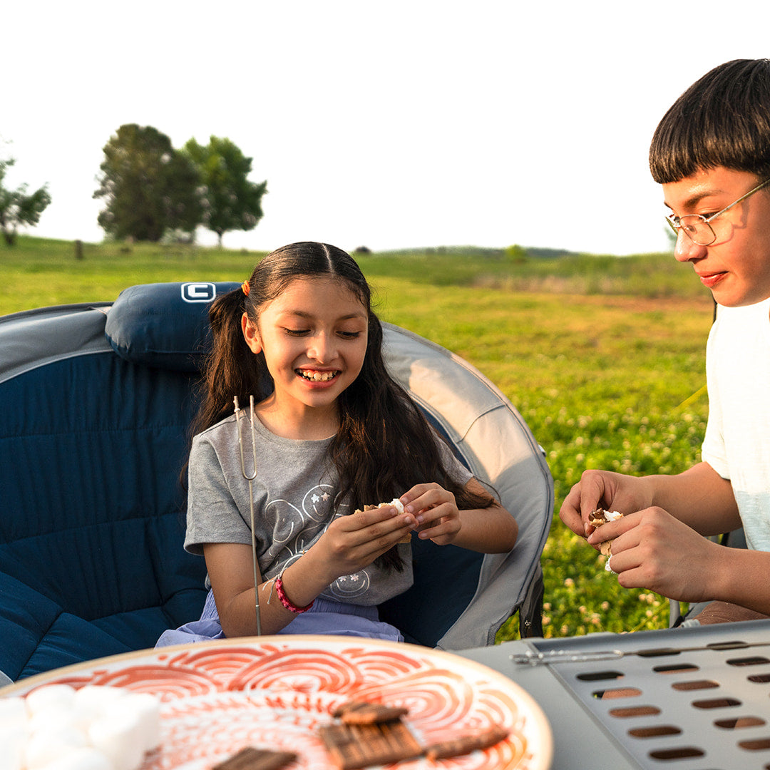 Kids making s’mores outdoors with the CORE Padded Moon Chair in navy, featuring cushioned seat and foldable frame for comfort.