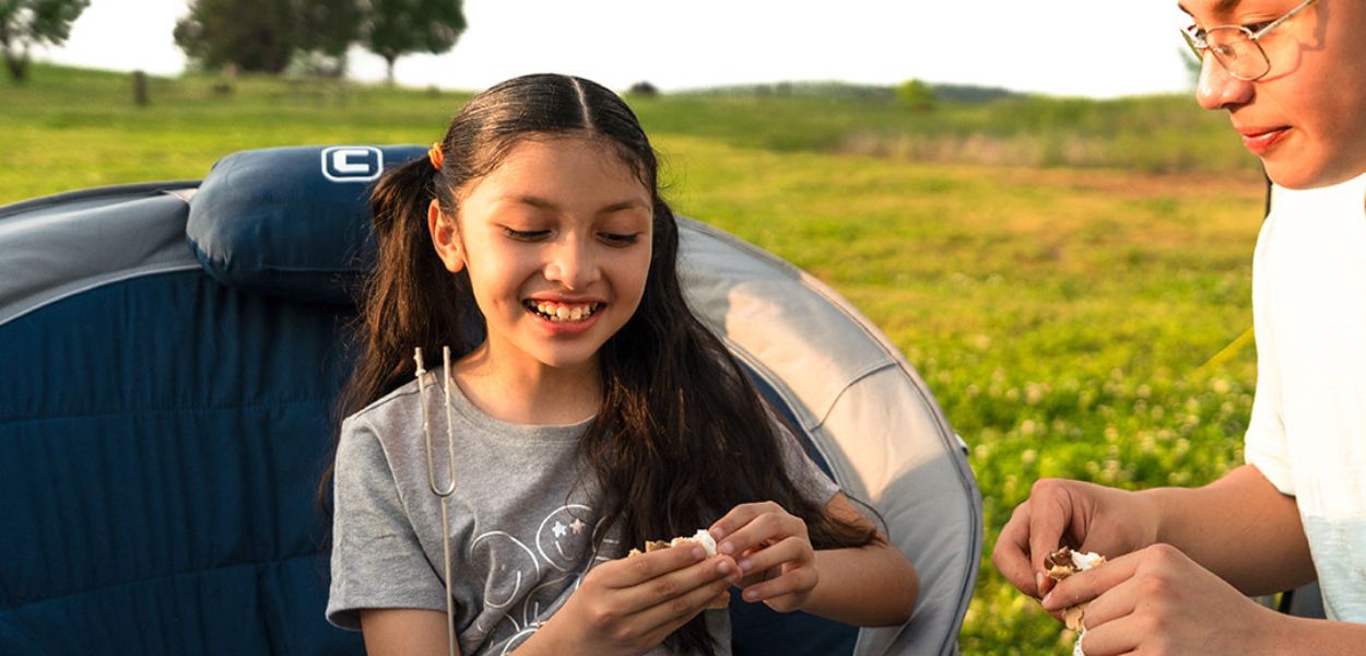 Kids making s’mores outdoors with the CORE Padded Moon Chair in navy, featuring cushioned seat and foldable frame for comfort.
