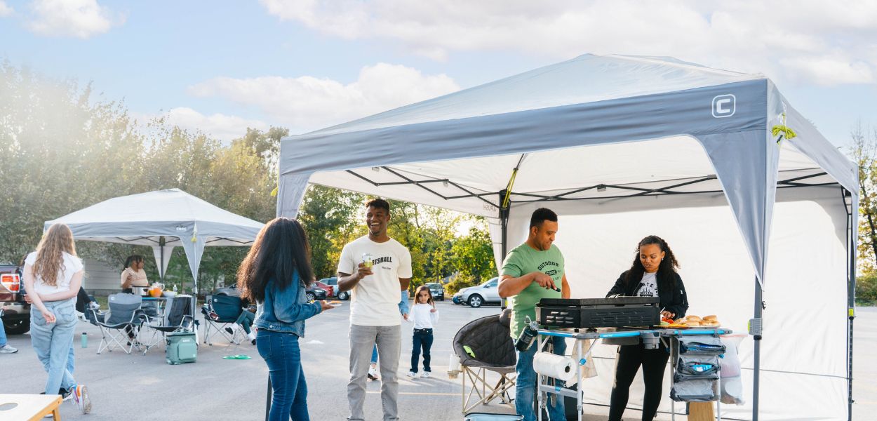 A group of campers are tailgating with the CORE 10x10 Center Push Canopy