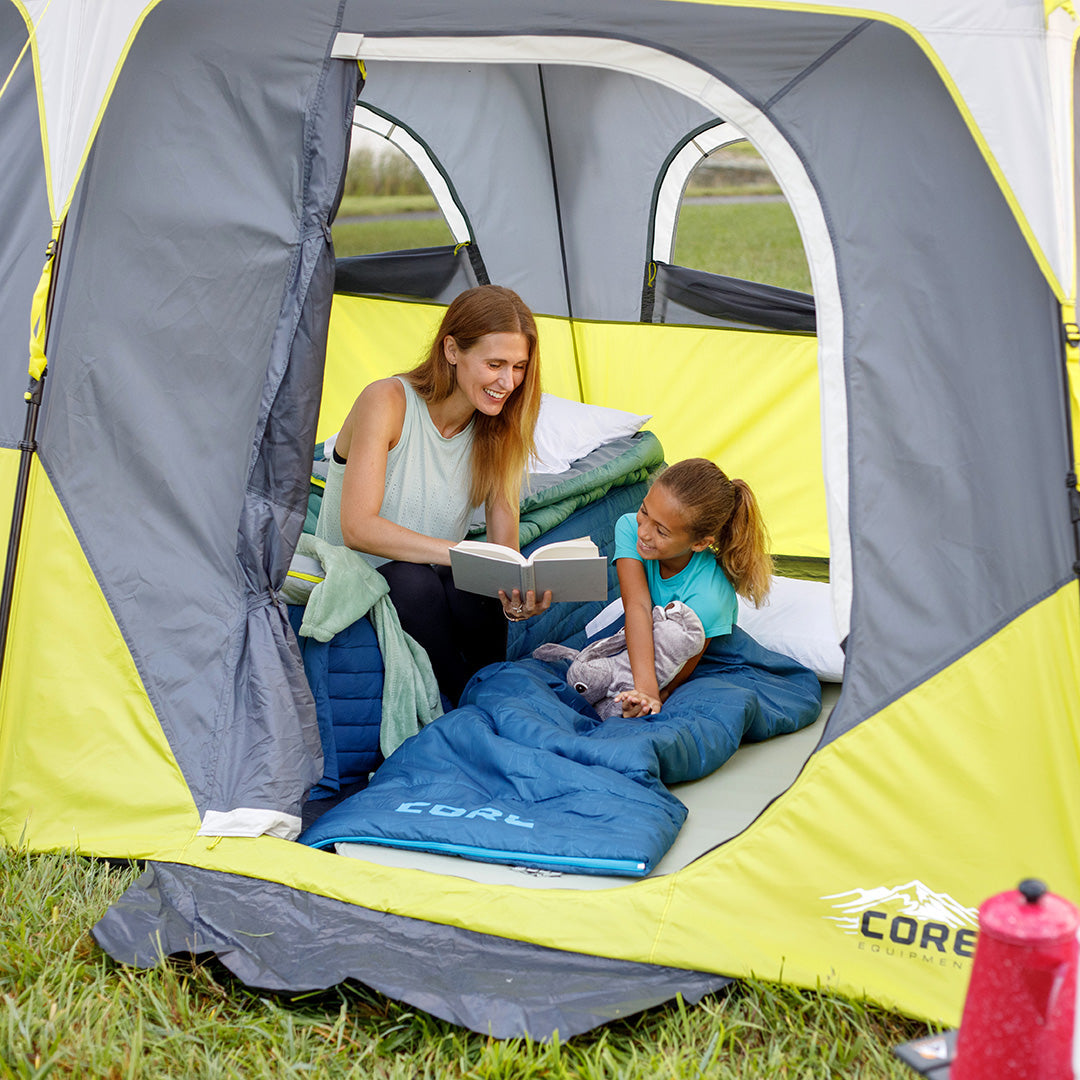 Mom and daughter reading inside a CORE tent with sleeping bags, showing spacious interior and weather protection.