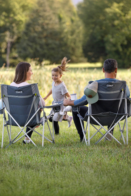 Family sitting in Core camp chairs in a field.