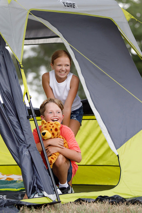 Two children peeking out from a CORE 10 person instant cabin tent with a stuffed animal.