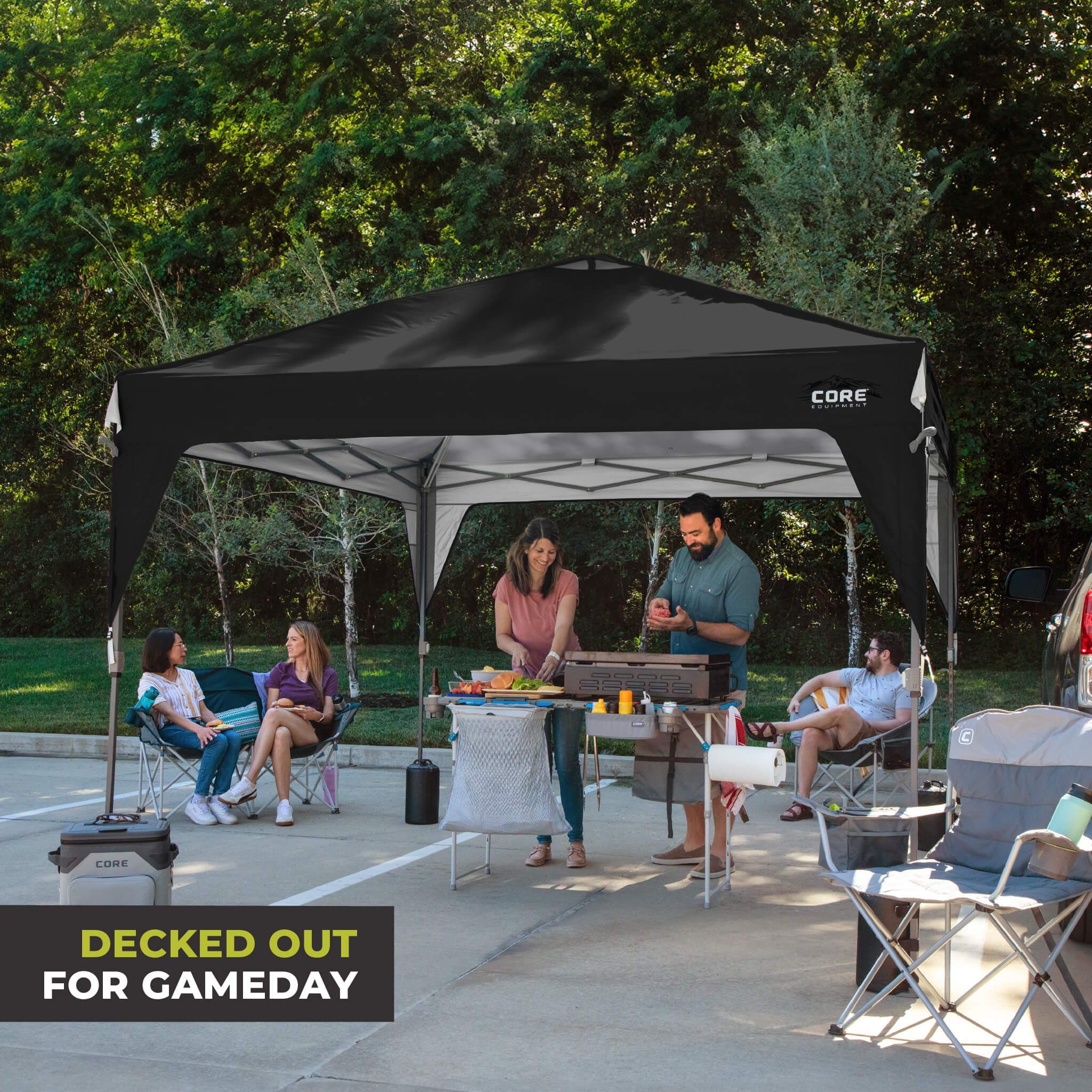 Friends relaxing outdoors under the CORE 10x10 Center Push canopy top in black, providing shade and ventilation for gatherings.