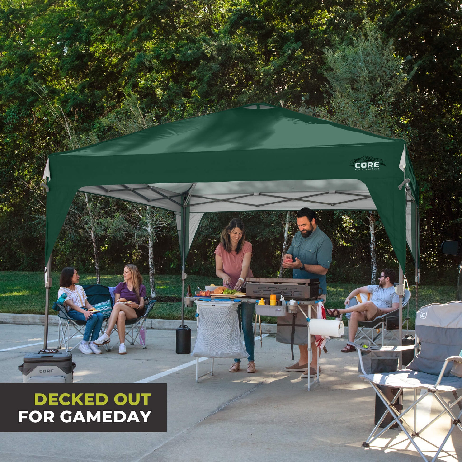 Friends relaxing outdoors under the CORE 10x10 Center Push canopy top in forest green, providing shade and ventilation for gatherings.