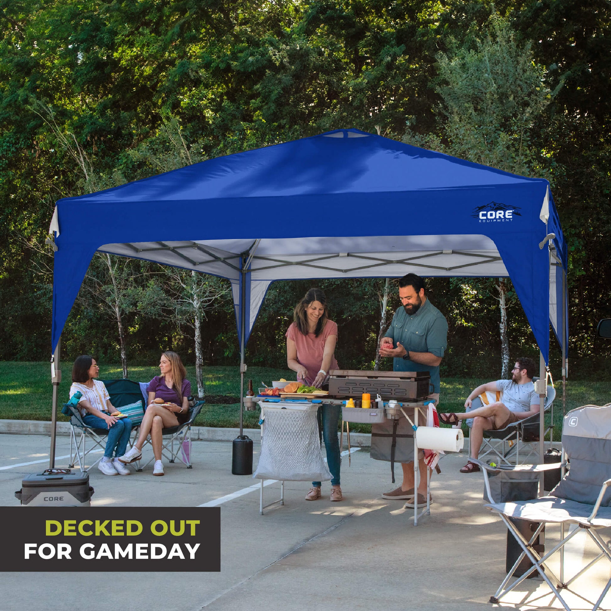 Friends relaxing outdoors under the CORE 10x10 Center Push canopy top in royal blue, providing shade and ventilation for gatherings.