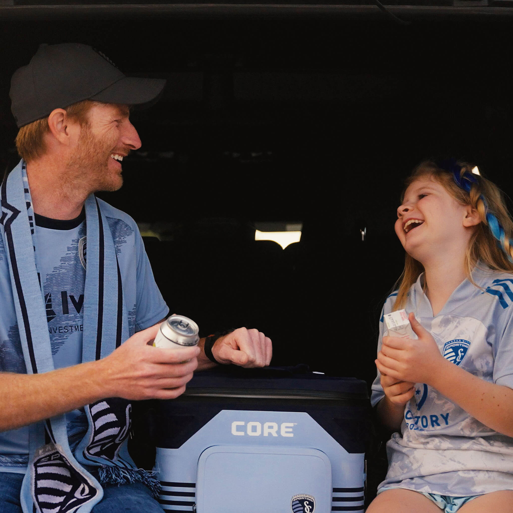 Father and daughter are enjoying drinks at a Sporting KC tailgate with a limited edition CORE Climakeep 18 can cooler in light blue and navy.