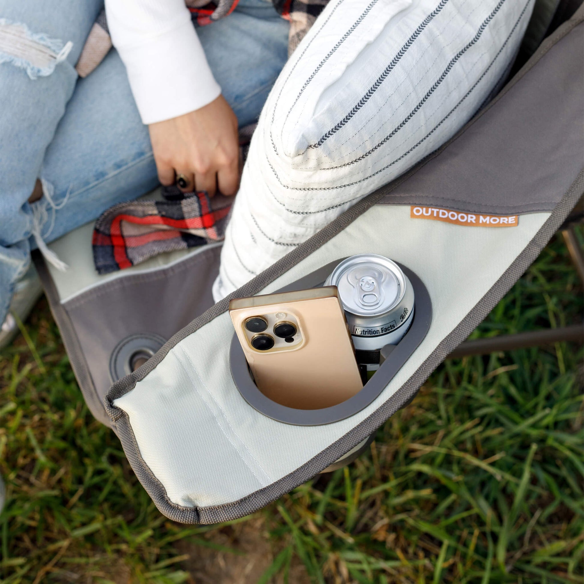 Close-up of CORE brown and beige loveseat chair armrest with cup holder holding a can and phone storage pocket.