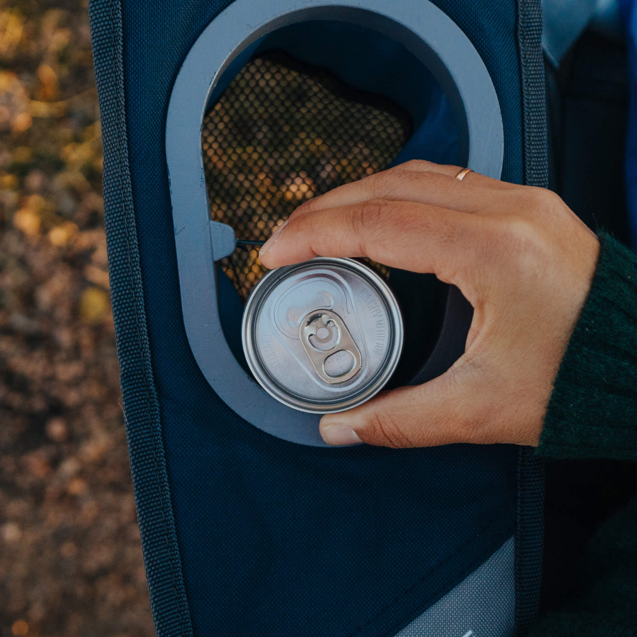 Close-up of hand placing can in CORE navy loveseat cup holder.
