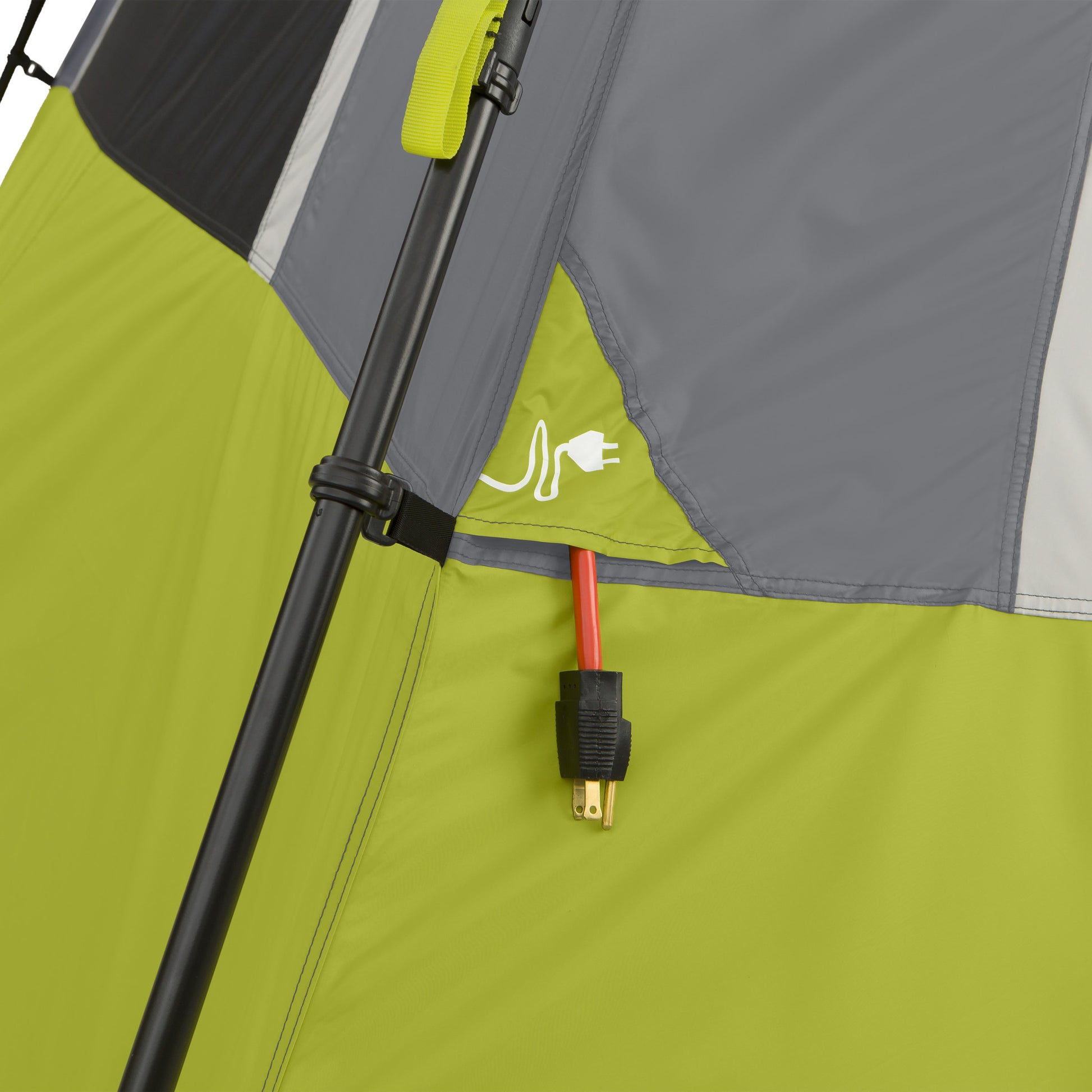 A close-up of a tent wall shows a power cord accessing the tent's interior through a specialized flap. The flap features a electrical plug icon, and the tent fabric is mainly green and gray. A black tent pole is partially visible. The tent is the 6 Person Instant Cabin Tent by CORE.