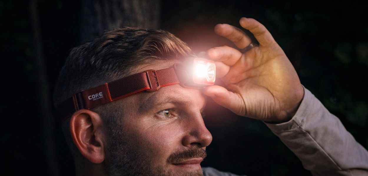 A man wearing a CORE 600 lumen rechargeable headlamp at night.