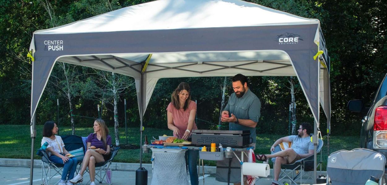 Group relaxing under CORE canopy with center push setup, providing shade and UV protection for outdoor gatherings.