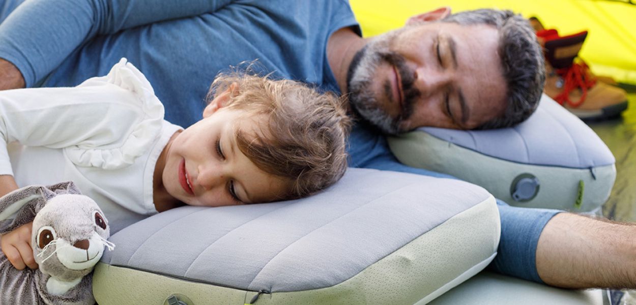 Father and daughter sleeping on a CORE inflatable camp bed and pillows inside a CORE 9 person instant cabin camping tent, with a stuffed bunny toy.