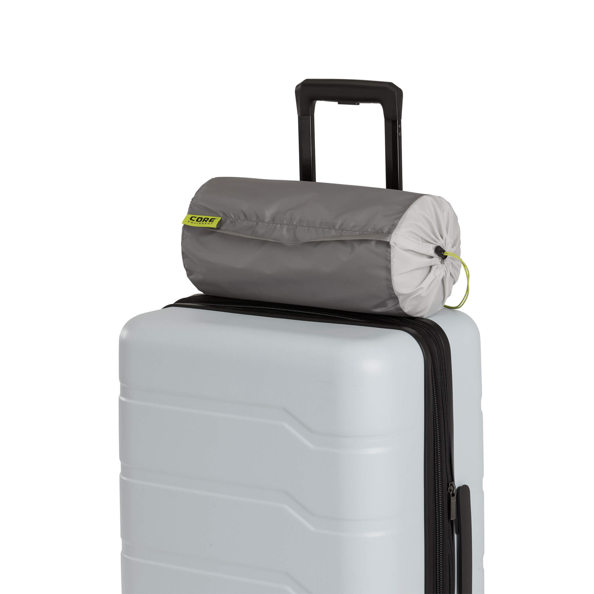 Compact gray travel pillow in a drawstring carry bag resting on top of a hard-shell suitcase with an extended handle, showing travel-ready portability and convenience.