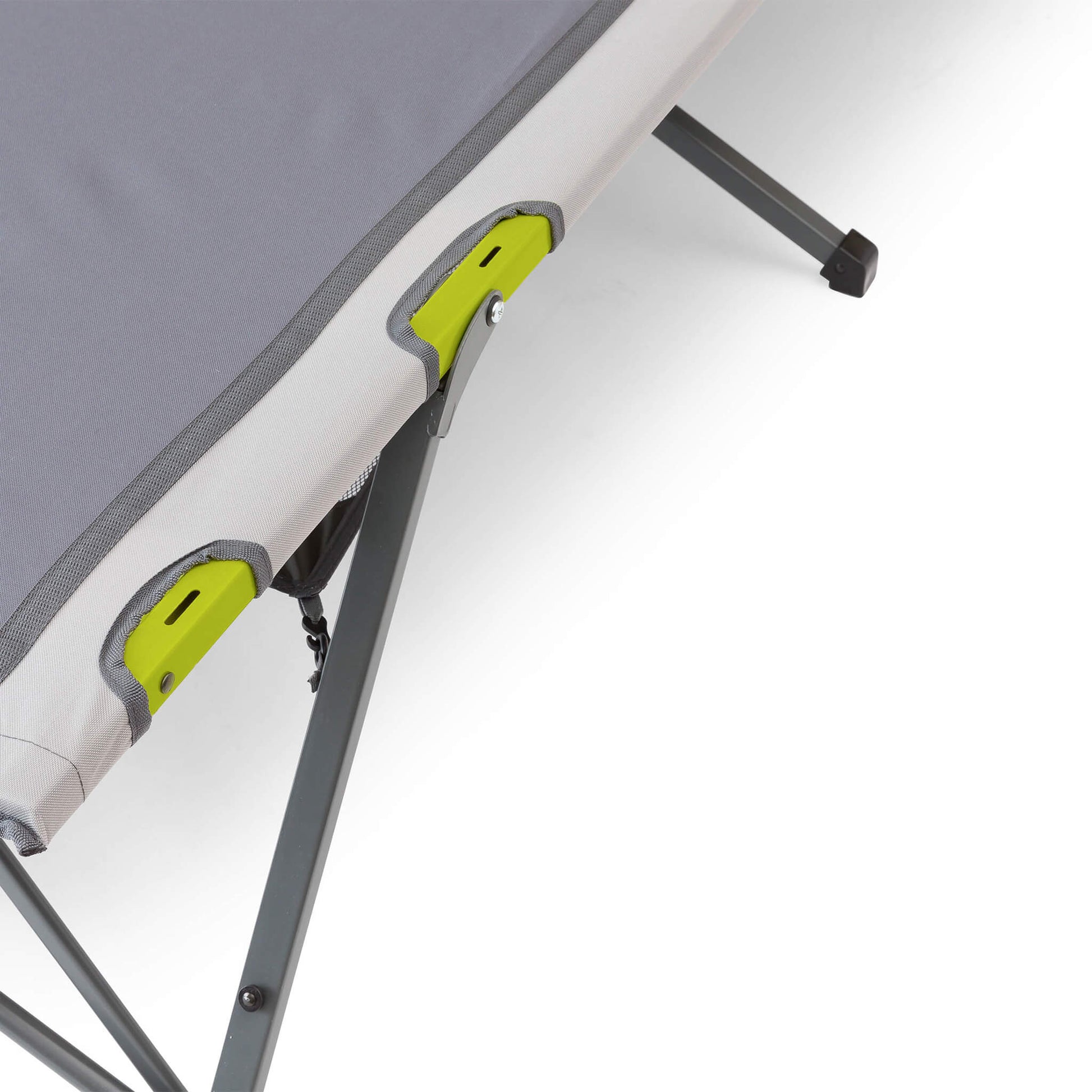Close-up of a camping cot with a gray cushion and a green frame with slots for a cup holder.