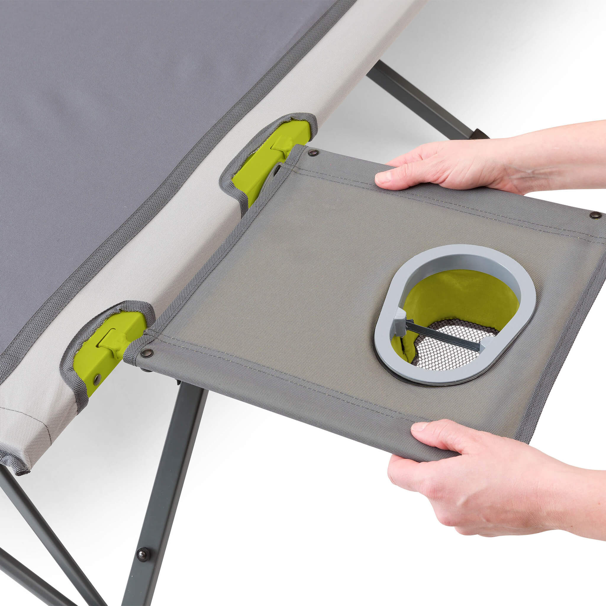 Person holding a gray and green camping side table with a built in cup holder attached to a CORE cot.