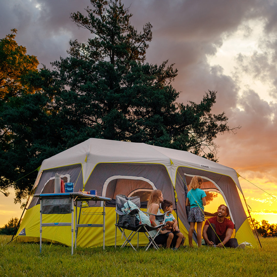 Family camping outdoors with a CORE 8 Person Instant Cabin Tent and a sunset sky