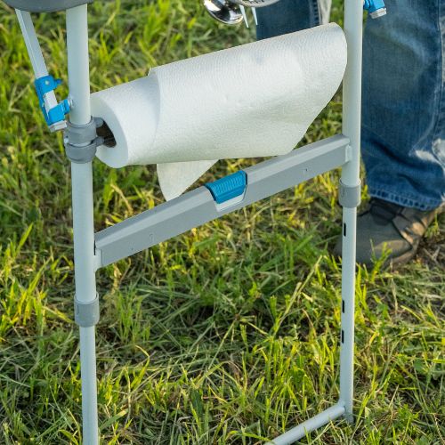 Camping table leg with single-hand height adjustment and mounted paper towel holder on CORE FlexRail system, set up on grass for outdoor use
