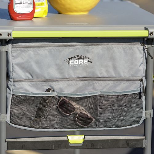 CORE FlexRail camping table with attached storage bag featuring zippered compartments and mesh pocket holding sunglasses, designed for organized outdoor gear storage
