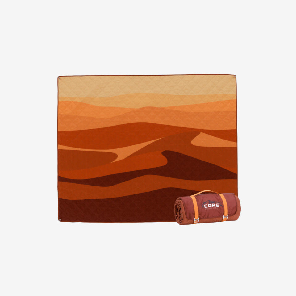 Orange and red patterned weighted camp blanket laid out with it rolled up next to it.