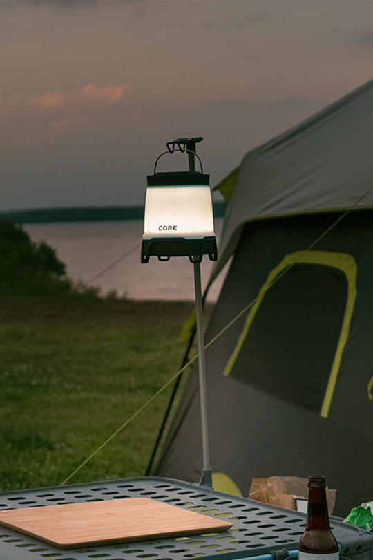 Camping scene with a lantern, CORE tent and Flexrail table by the lake. 
