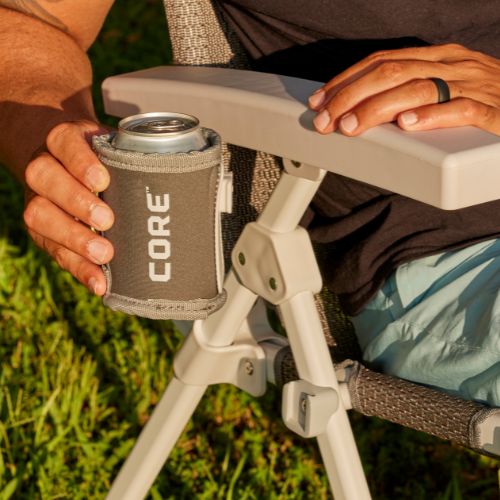 Removable fabric cup holder attached to a hard arm camping chair, securely holding a beverage can within easy reach.
