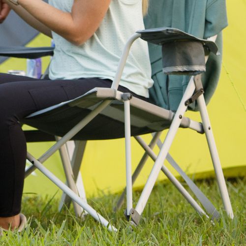 Folding outdoor chair with a tension-locking frame design, showing reinforced crossbars and joints for added stability, with a built-in armrest organizer, set on grass near a camping tent.