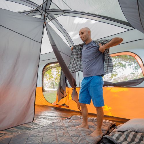 A person standing inside a CORE 10 person straight wall cabin tent.