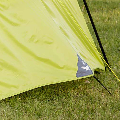 Close-up of a CORE 10 person instant tent ventilation showing durable green fabric, reinforced seams, and guyline attachment set up on grass.