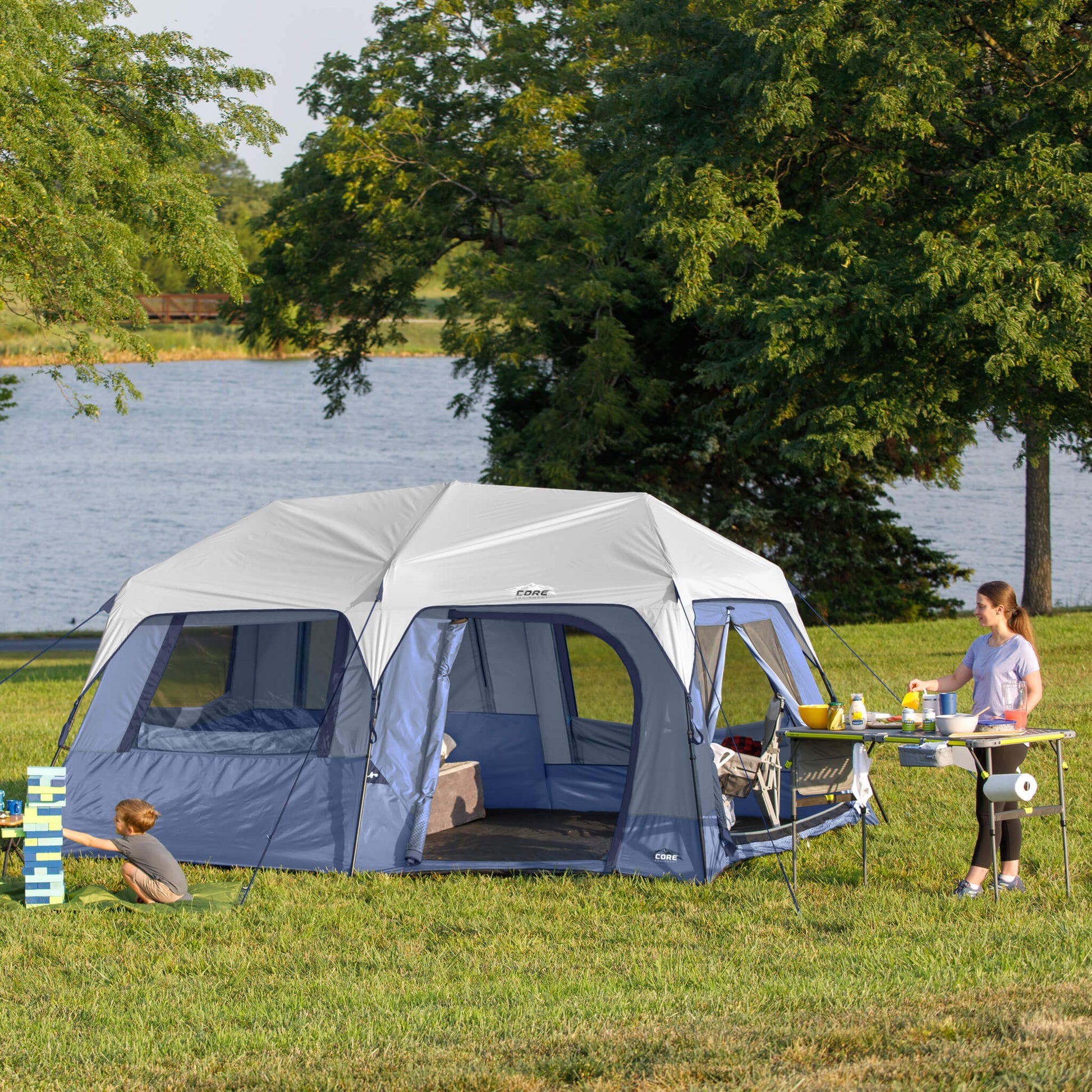 Family camping beside CORE 10 person instant cabin tent, showing spacious outdoor setup and easy access doors.