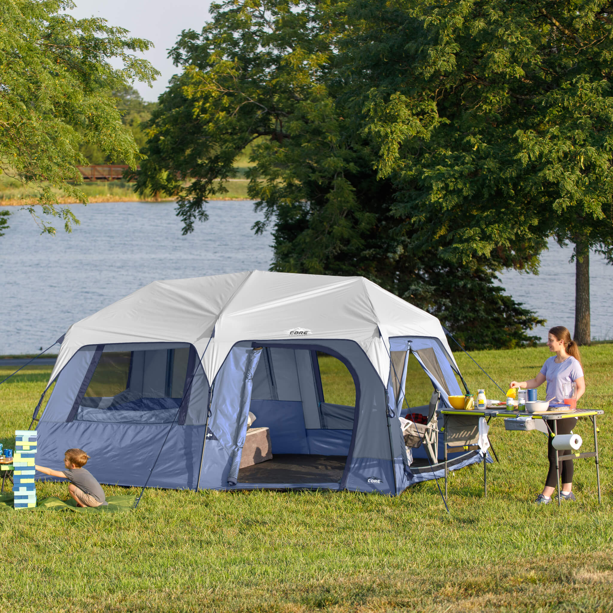 Family camping beside CORE 10 person instant cabin tent, showing spacious outdoor setup and easy access doors.
