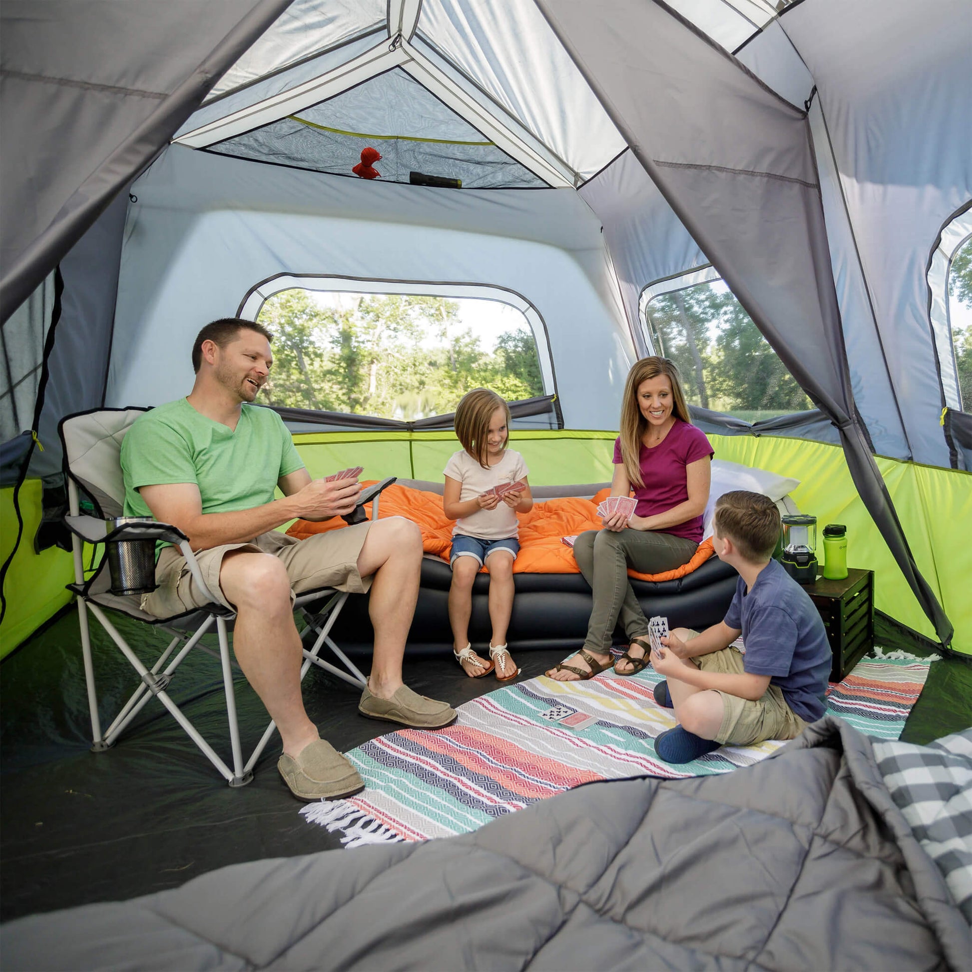 Family enjoying time inside the CORE 10 person instant cabin tent with screen room in gray and green, offering durable weather protection and comfort.