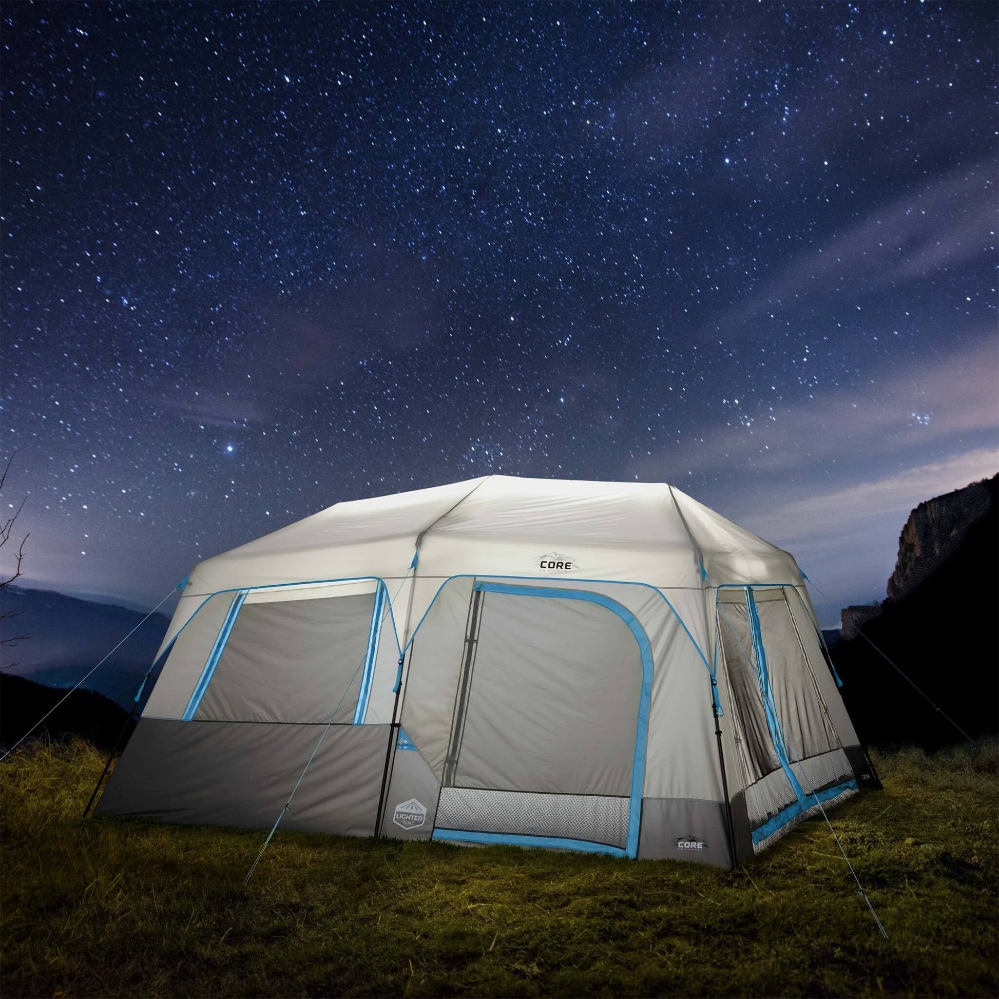 CORE 10 person lighted instant cabin tent in gray and blue, glowing at night, showing spacious design, weather protection, and LED lighting.