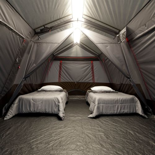 Two beds inside a large gray tent with red accents.
