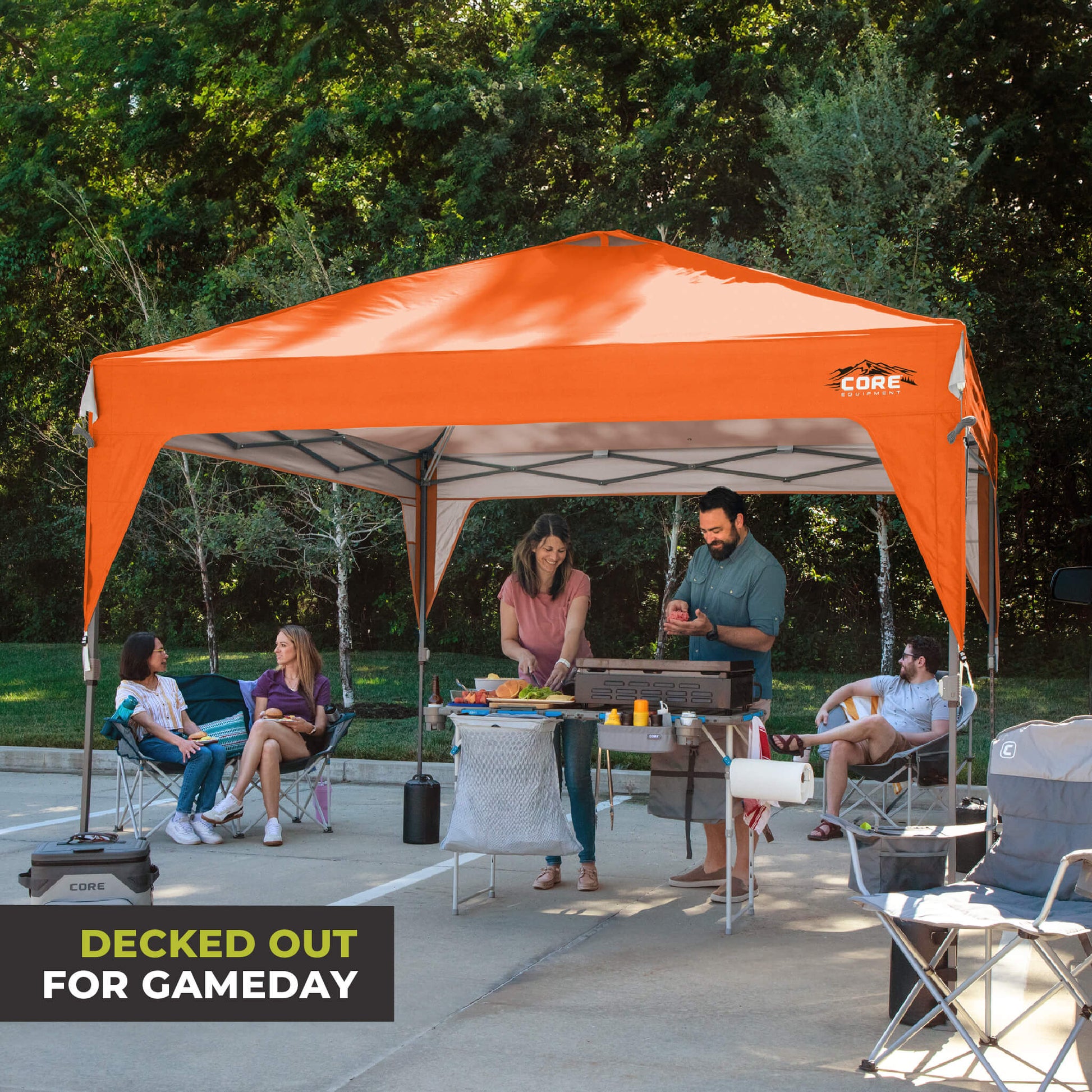 Friends relaxing outdoors under the CORE 10x10 Center Push canopy top in orange, providing shade and ventilation for gatherings.