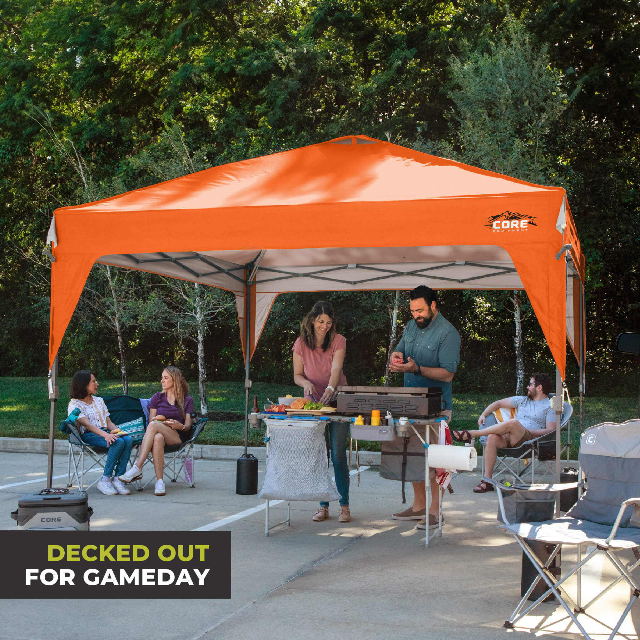 Friends relaxing outdoors under the CORE 10x10 Center Push canopy top in orange, providing shade and ventilation for gatherings.