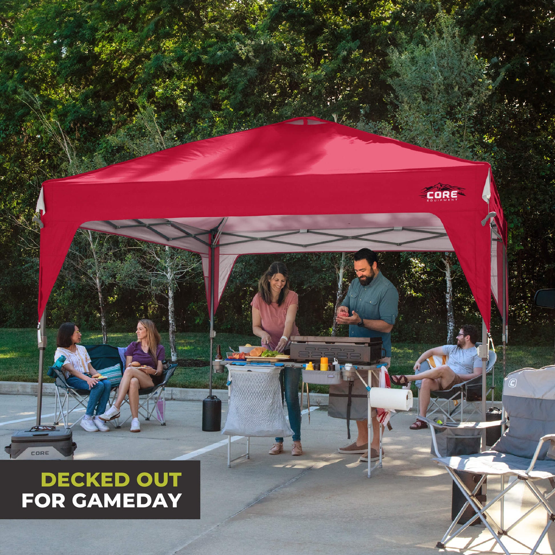 Friends relaxing outdoors under the CORE 10x10 Center Push canopy top in red, providing shade and ventilation for gatherings.