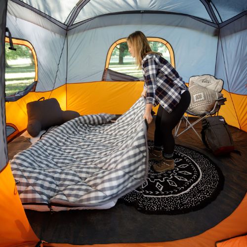 A person standing up in a CORE 11 person cabin tent with screen room.