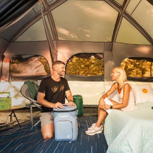 Two people sitting inside a CORE 12 person straight wall cabin tent with full rainfly.