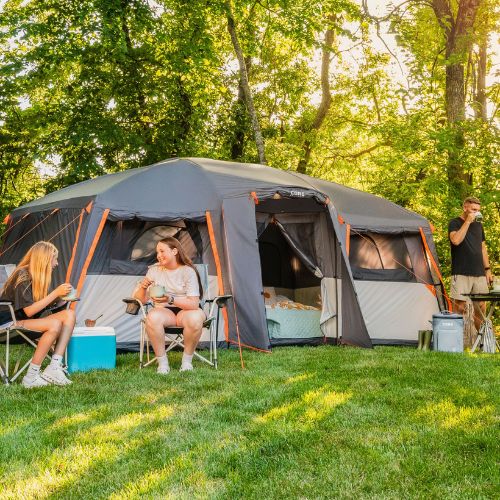 People camping outdoors with a CORE 12 person straight wall cabin tent in a wooded area.
