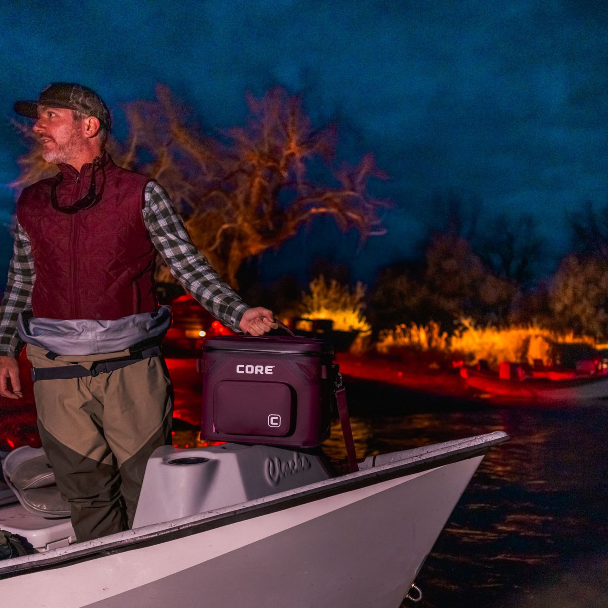 A man is on a boat with a CORE 18 can Mulberry climakeep cooler.