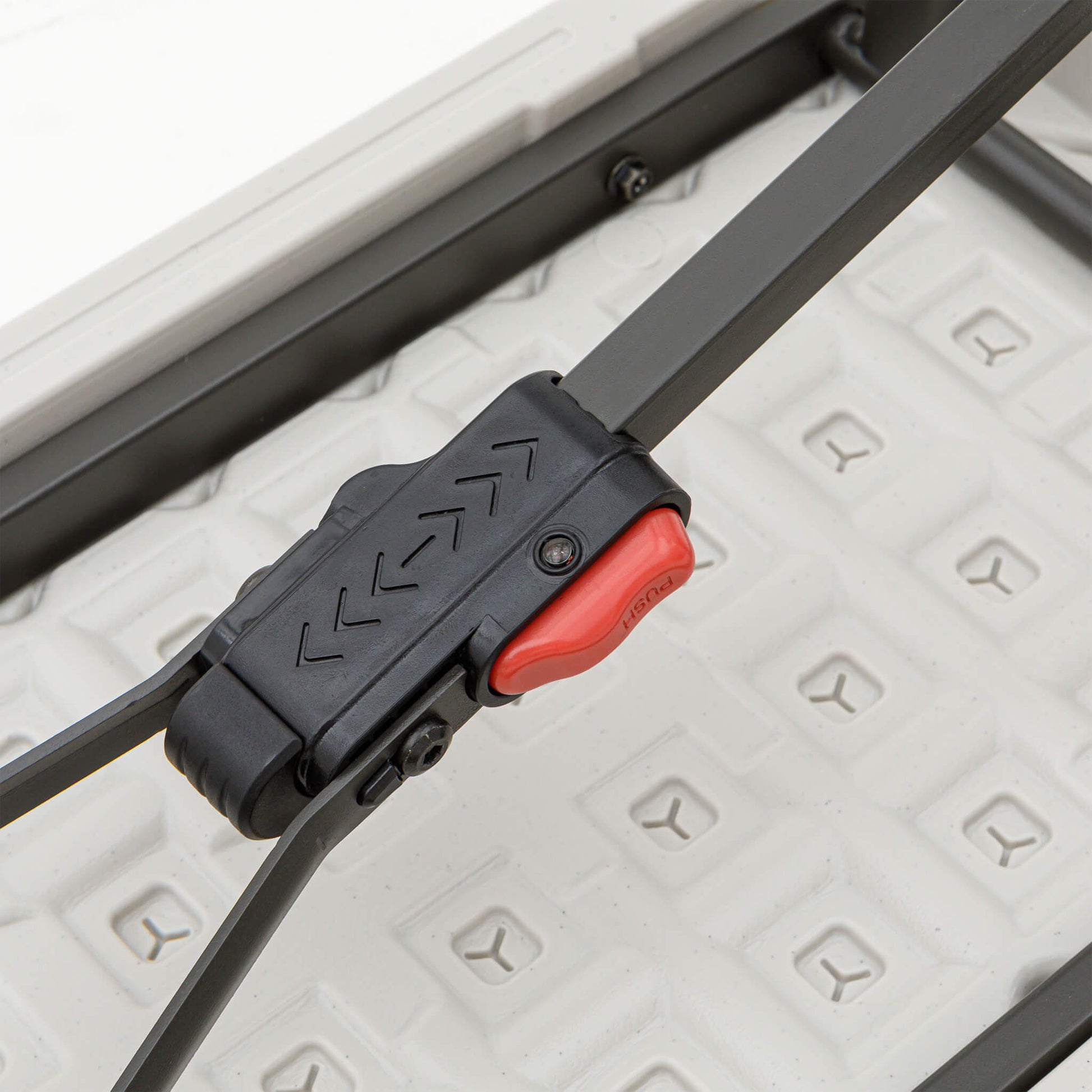 Detail of CORE folding bench leg locking mechanism with secure red latch for added stability.