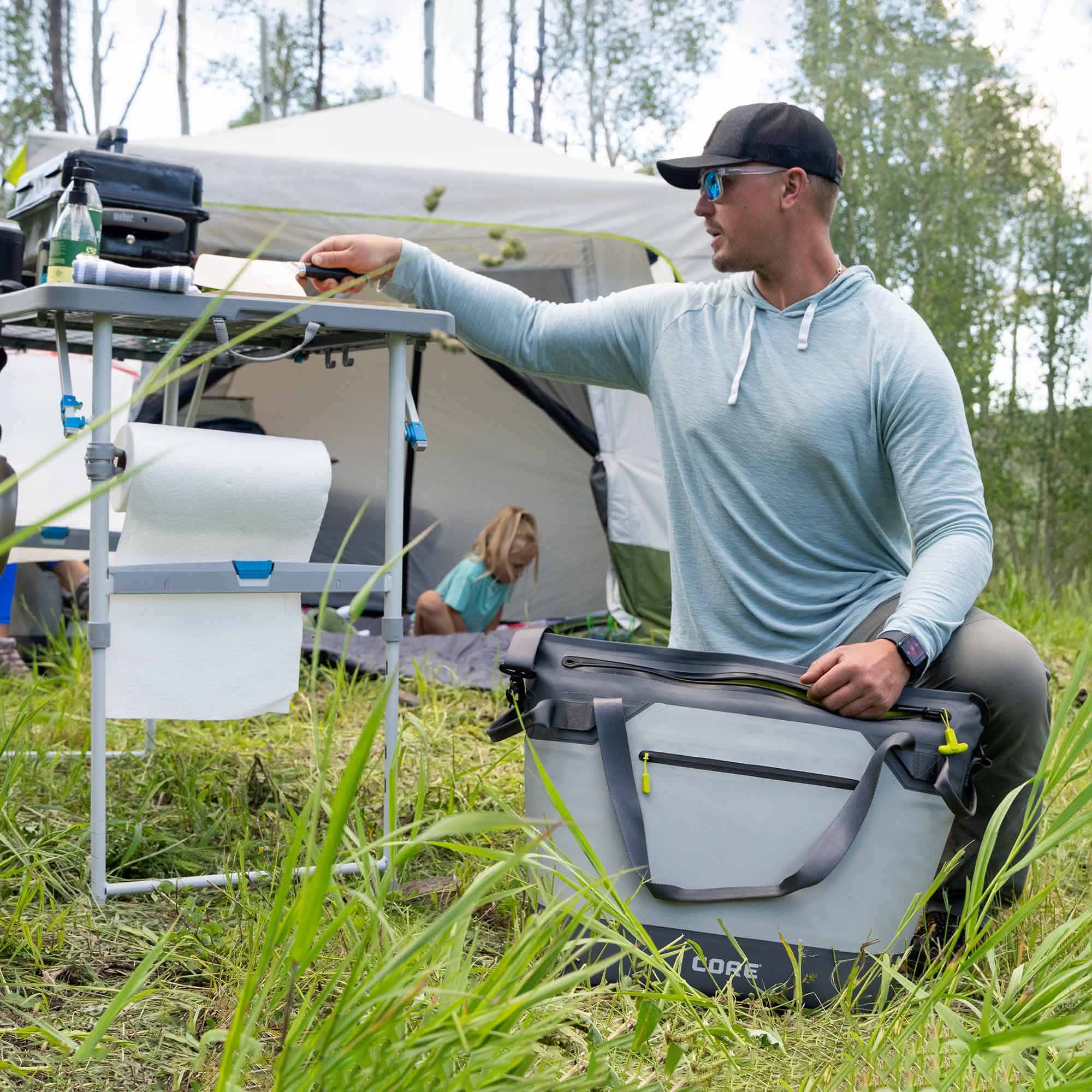 CORE 20 can performance cooler in gray shown outdoors beside camp table, ideal for keeping drinks cold on trips.
