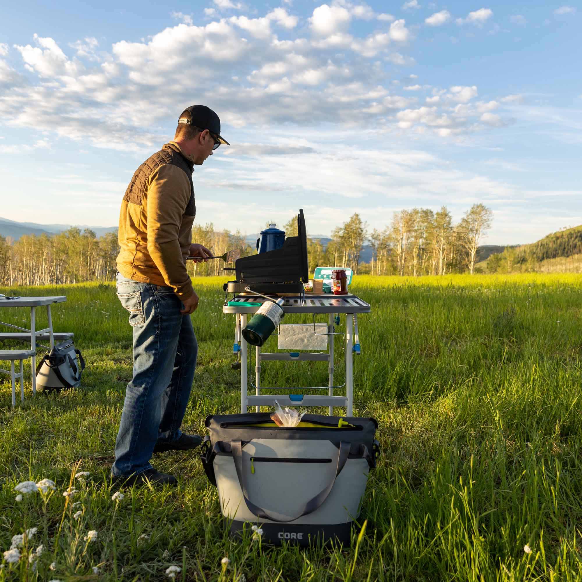 CORE 30 can performance cooler in gray shown outdoors beside camp table, ideal for keeping drinks cold on trips.