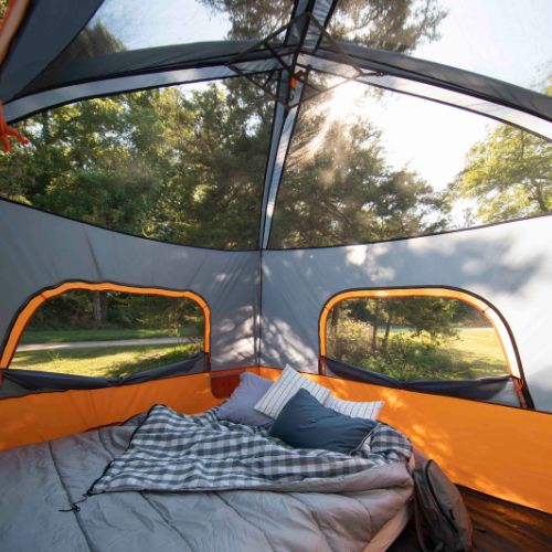 CORE 4 person straight wall cabin tent interior with bed, pillows, and a small table in a forest setting.