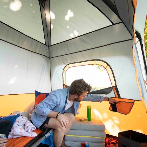 A person putting a phone inside a storage pocket inside a tent.