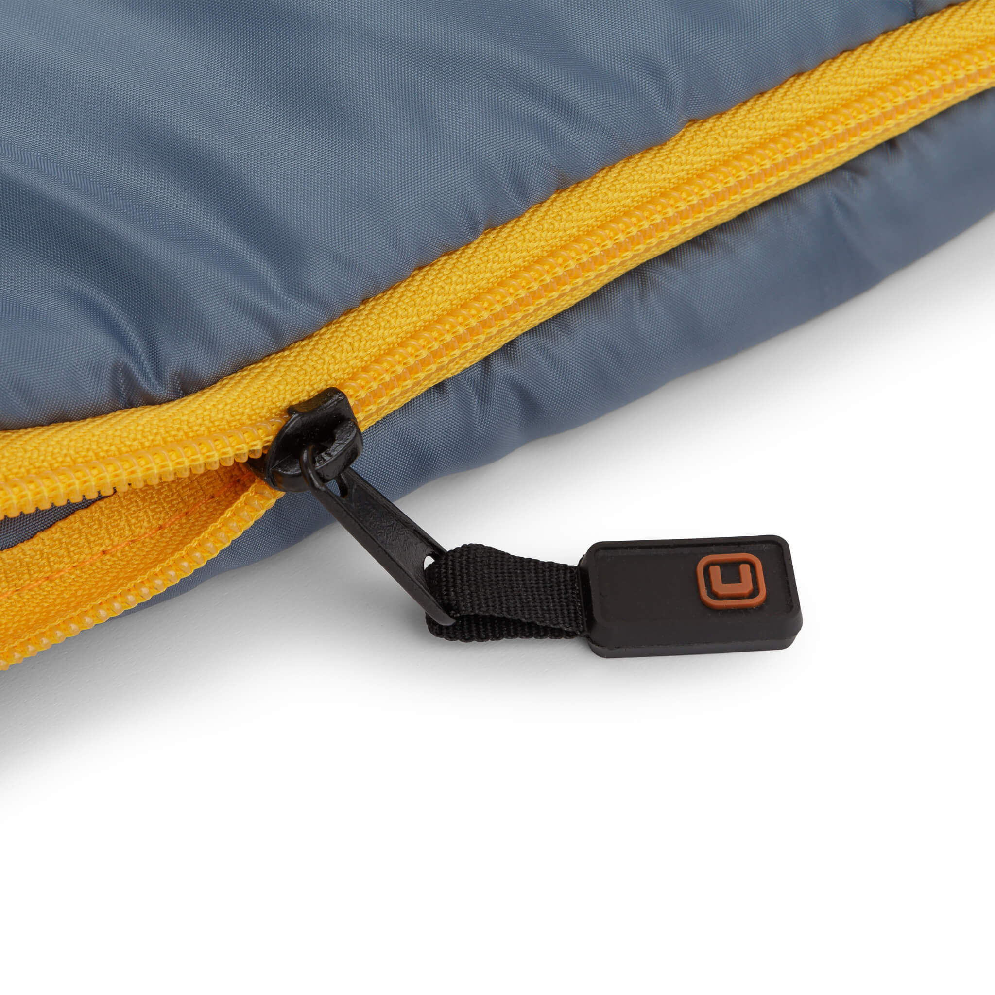 Close-up of CORE sleeping bag zipper with orange trim and black pull tab.