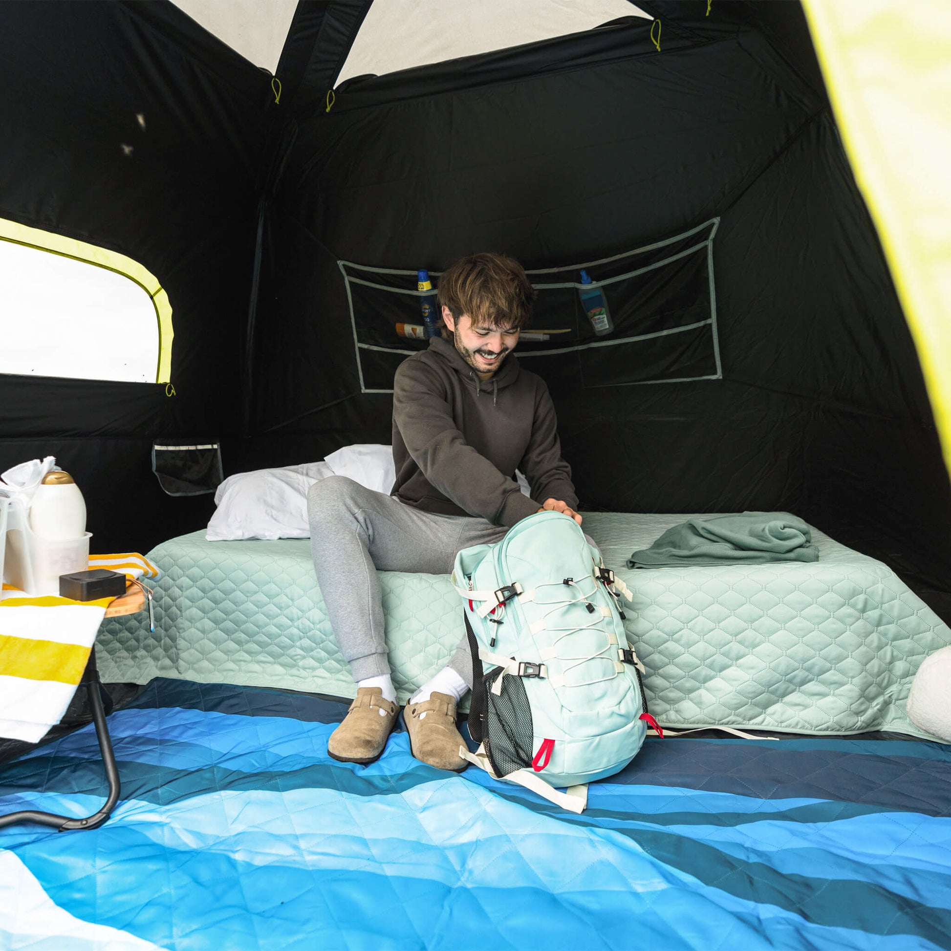 Camper sitting inside CORE 6 person Blockout instant cabin tent with dark interior and storage pockets for organized camping.