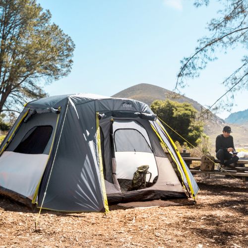 6 person instant cabin tent with full rainfly lifesyle with person sitting next to tent.