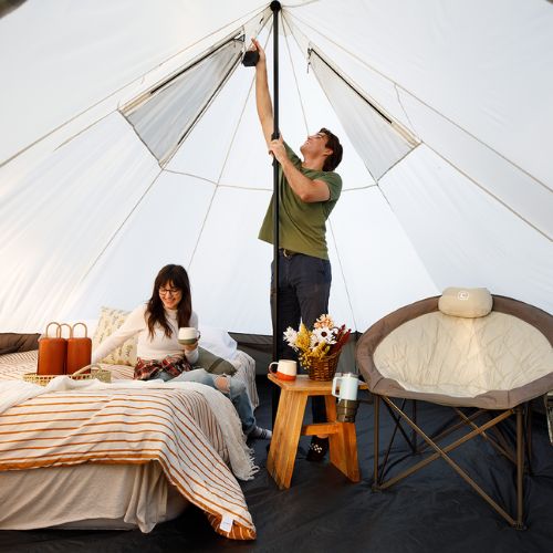 A person is standing and another is relaxing inside the CORE 6 person bell tent.