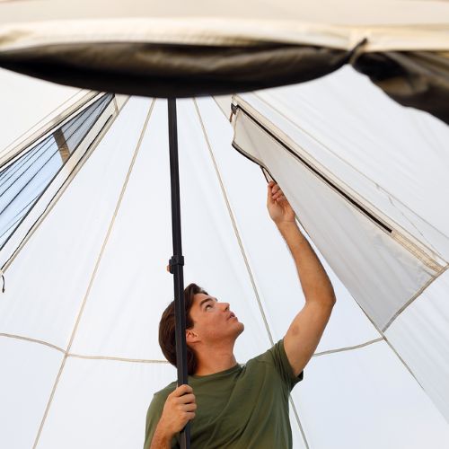 A person is adjusting a window on the CORE 6 person bell tent.